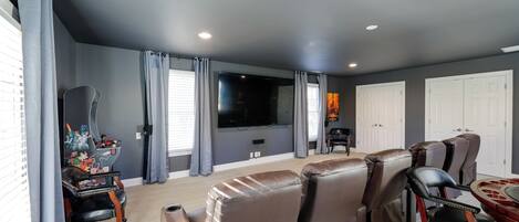 A living room with a flat-screen TV, leather recliners, a coffee table, and a wall-mounted TV.