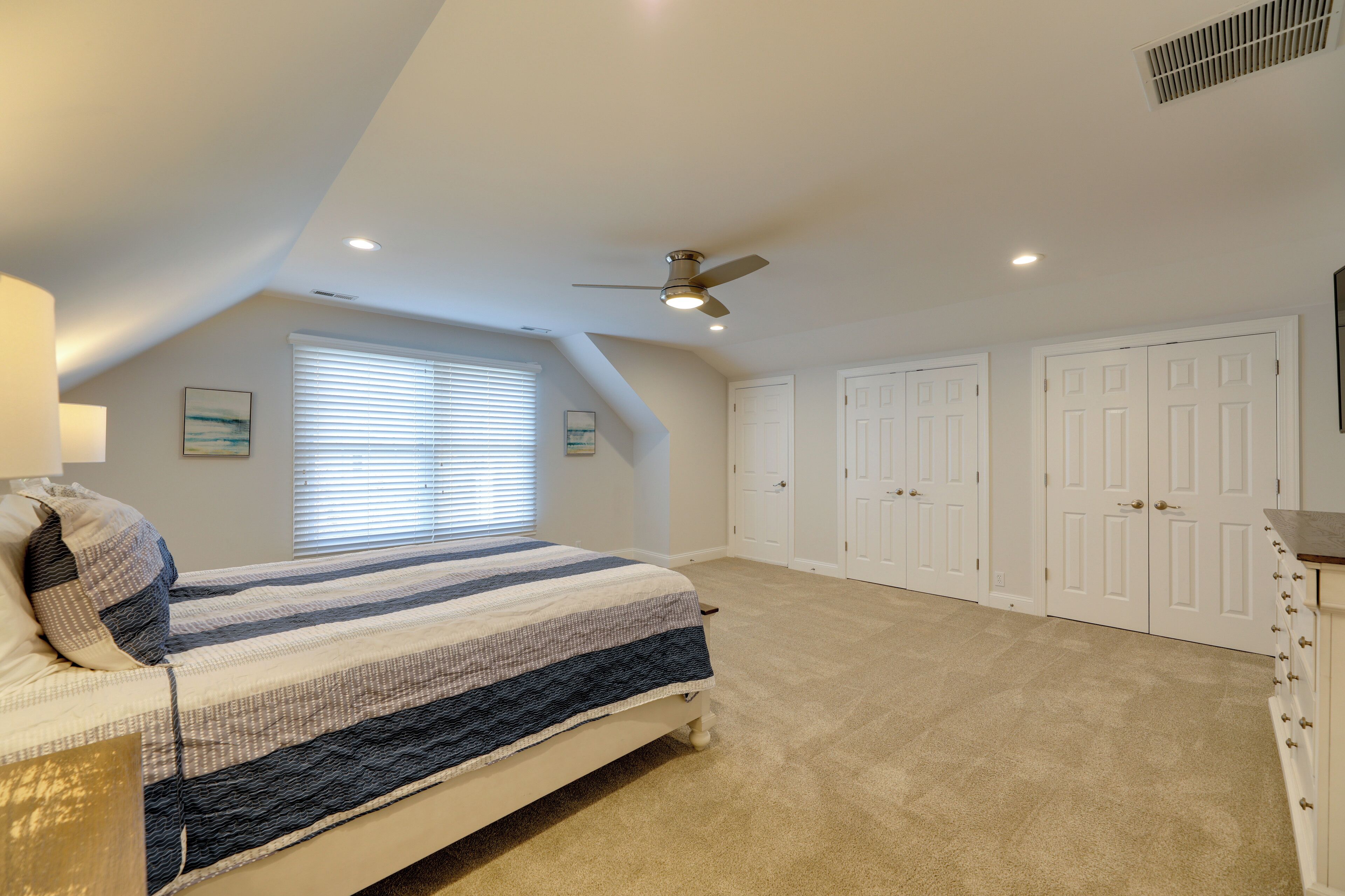 A bedroom with a bed, a ceiling fan, a window with blinds, and a closet with doors.