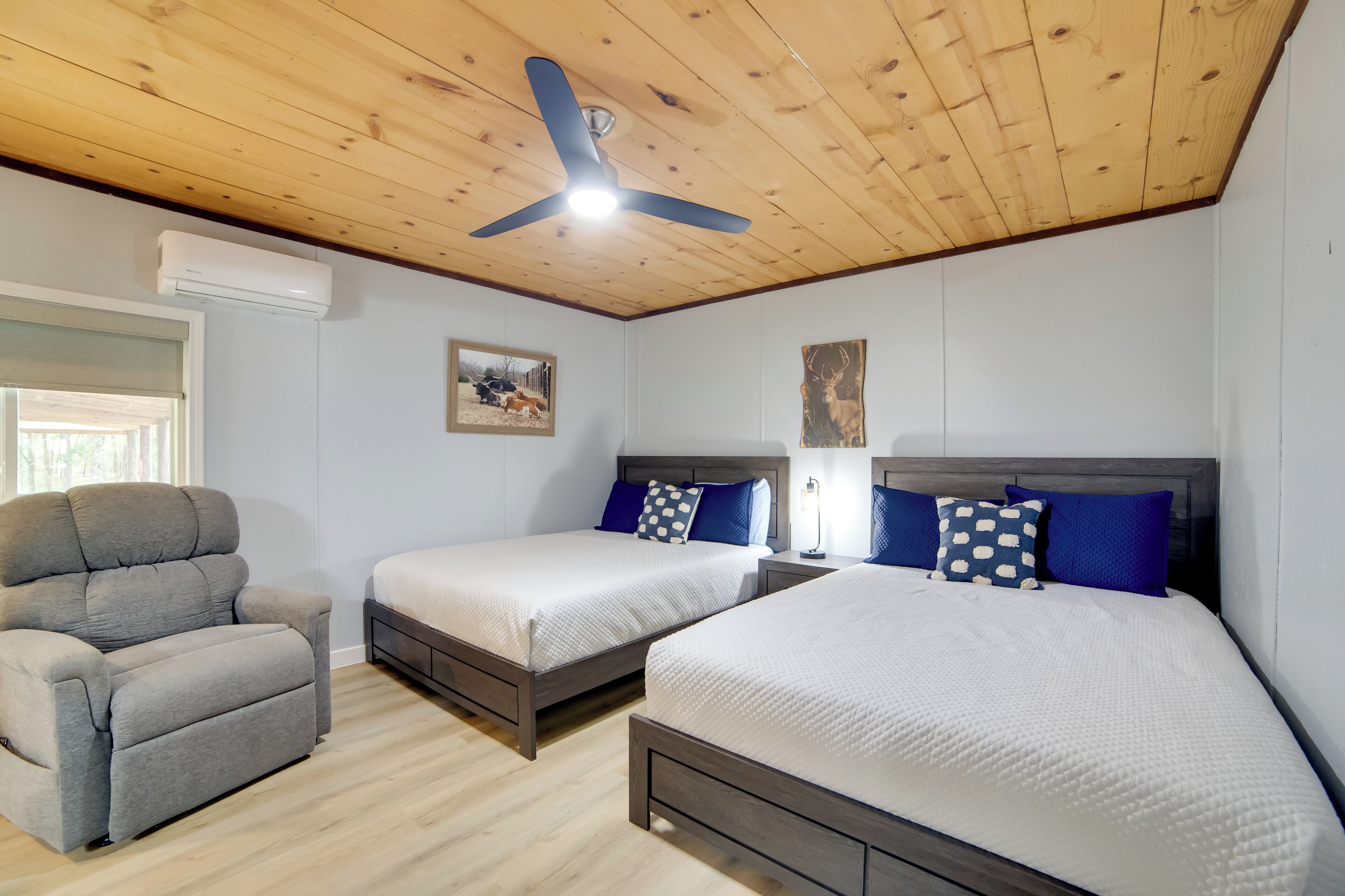A bedroom with two beds, a ceiling fan, and a window.