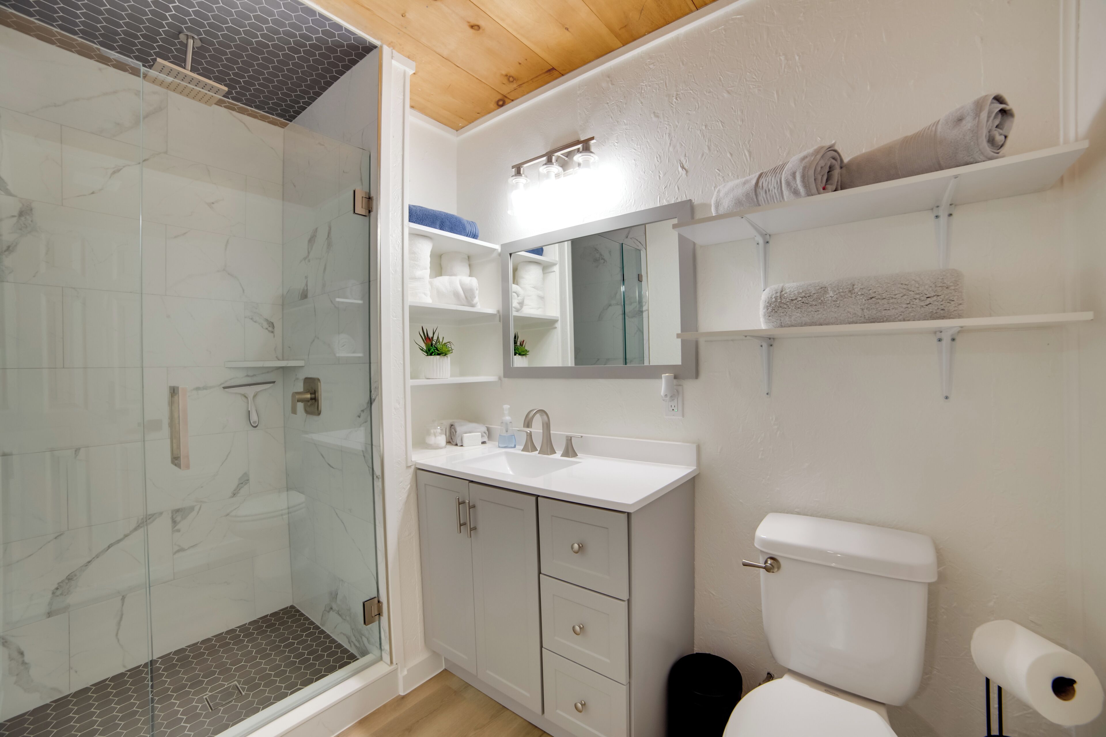 Un bany modern amb una cabina de dutxa de vidre, un lavabo blanc i un vàter.