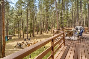 Terraza de madera con mobiliario exterior y vista a un bosque.