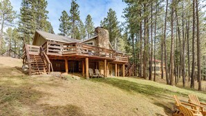 Eine Lodge mit Kamin aus Stein, einer Holzterrasse und Sitzgelegenheiten im Freien.