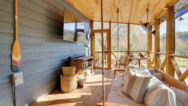 L’intérieur d’un chalet en bois comprend un lit, un téléviseur et une grande fenêtre donnant sur un paysage naturel.