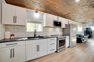 Una cocina moderna con gabinetes blancos, un refrigerador de acero inoxidable y un horno empotrado.