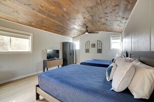 Un dormitorio con techo de madera, dos camas, un televisor y una ventana.