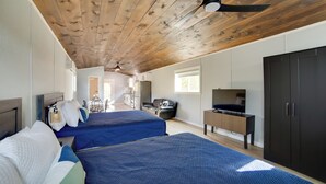 Een moderne hotelkamer met twee bedden, een plafondventilator, een televisie en een grote kledingkast.