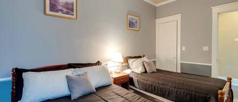 A bedroom with two beds, a nightstand, a lamp, and two framed pictures on the wall.