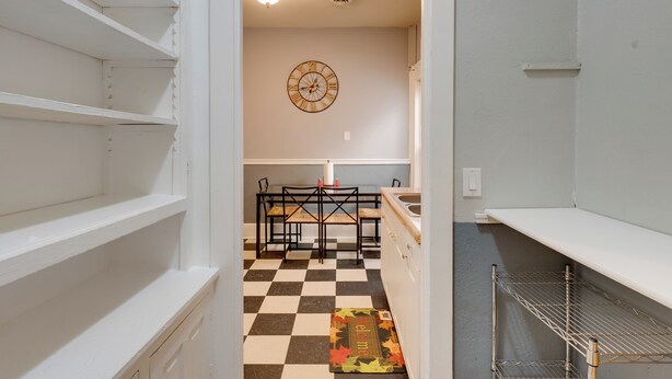 A kitchen with a checkered floor, a clock on the wall, and a welcome mat. - Walkable Racine Retreat! 1 Mi to Lake Michigan (Racine)