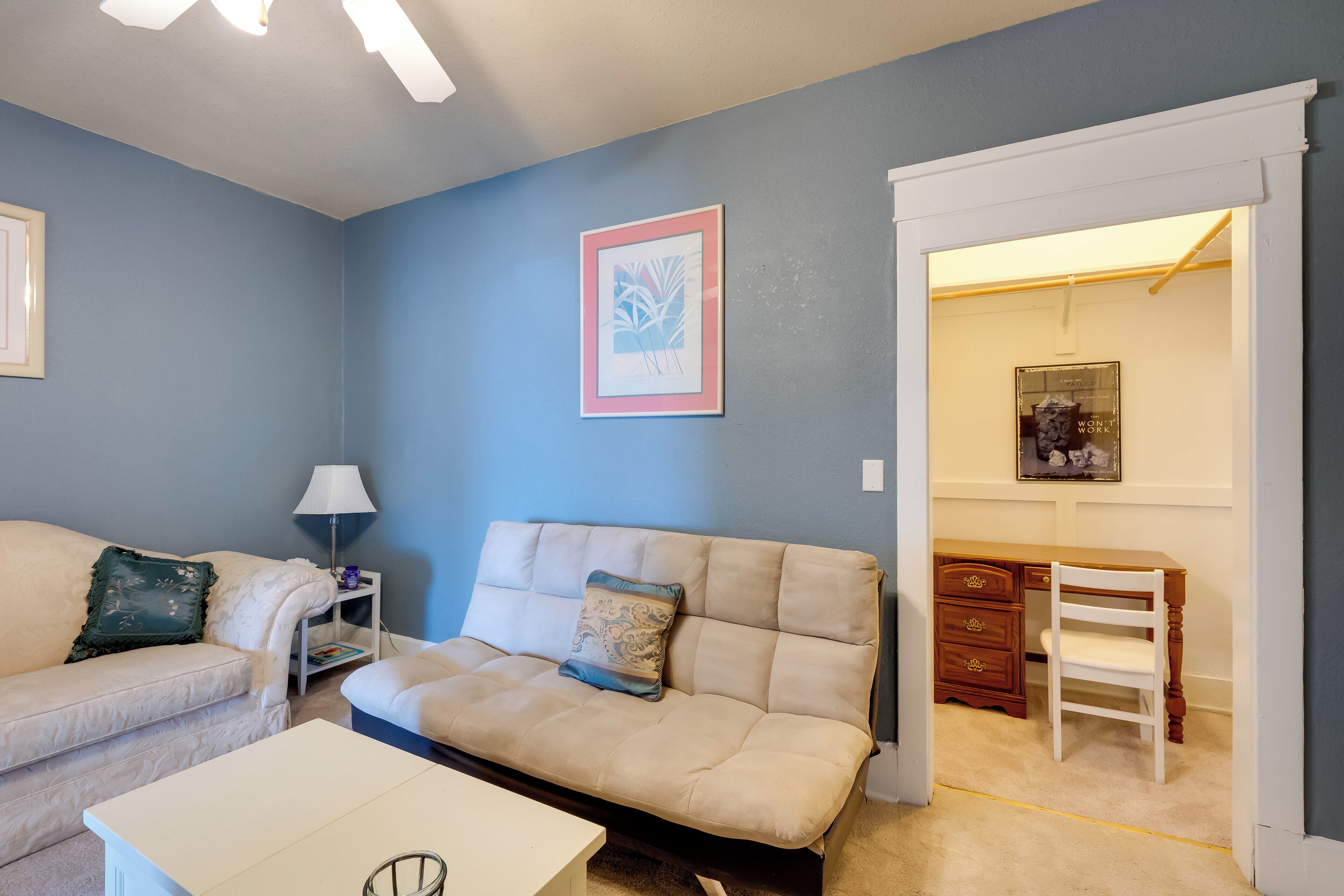 A living room with a beige sofa, a white coffee table, a lamp, and a framed picture on the wall.