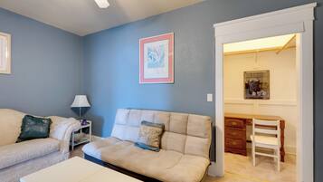 A living room with a beige sofa, a white coffee table, a lamp, and a framed picture on the wall.
