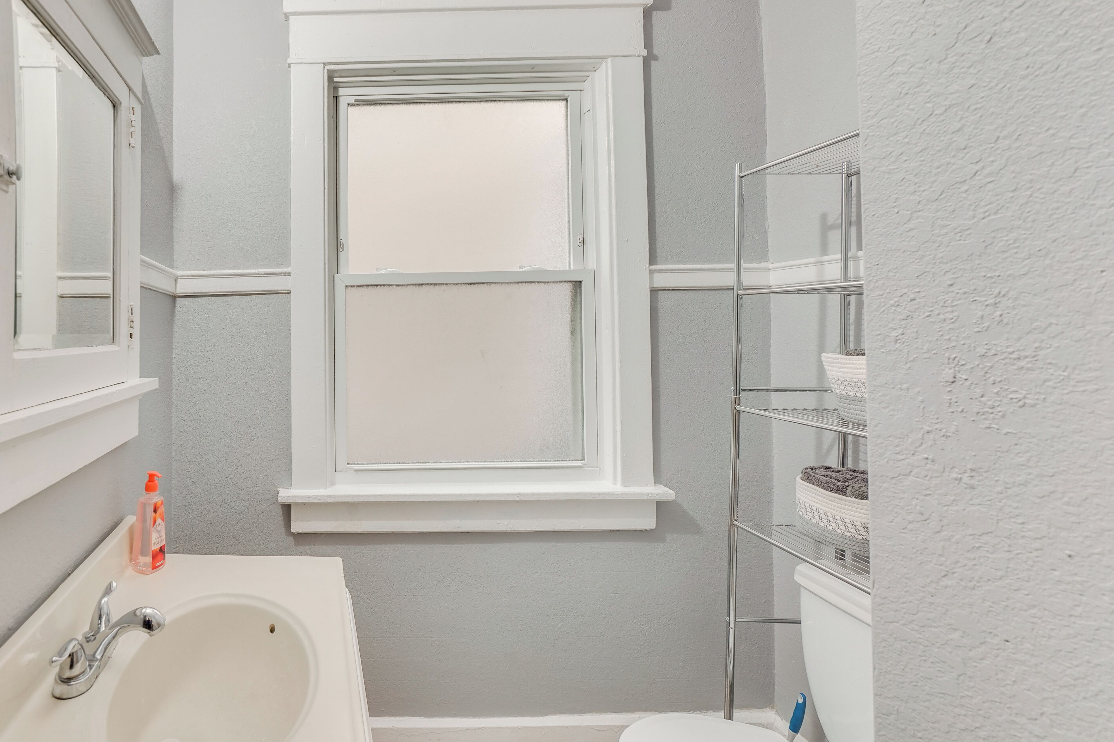 Ein Badezimmer mit einer weißen Badewanne, einem Fenster und einem Ablagebereich für Pflegeprodukte.