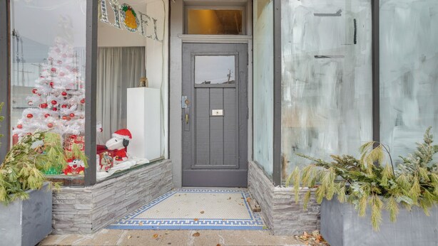 Una entrada principal con una puerta gris, un árbol de Navidad y una figura de Papá Noel en el interior.