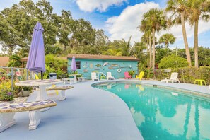 A pool area with a blue house, white and yellow chairs, and a purple umbrella. - Unwind Poolside + Walk to Lake! Okeechobee Getaway (Okeechobee)