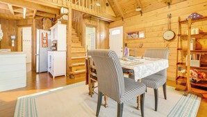 A cozy cabin interior with a dining area, kitchen, and a staircase leading to a loft. - Unwind Poolside + Walk to Lake! Okeechobee Getaway (Okeechobee)