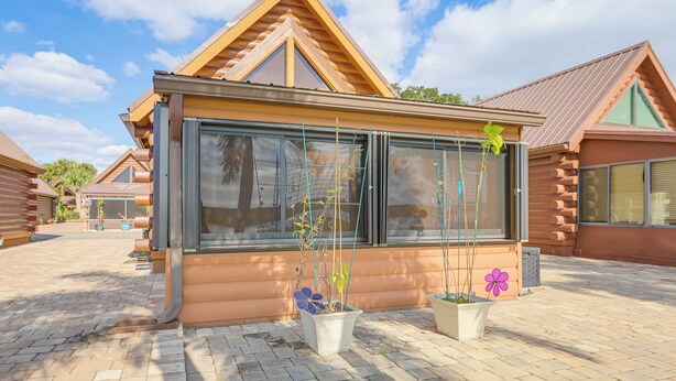A log cabin with large windows, potted plants, and a brick pathway. - Unwind Poolside + Walk to Lake! Okeechobee Getaway (Okeechobee)
