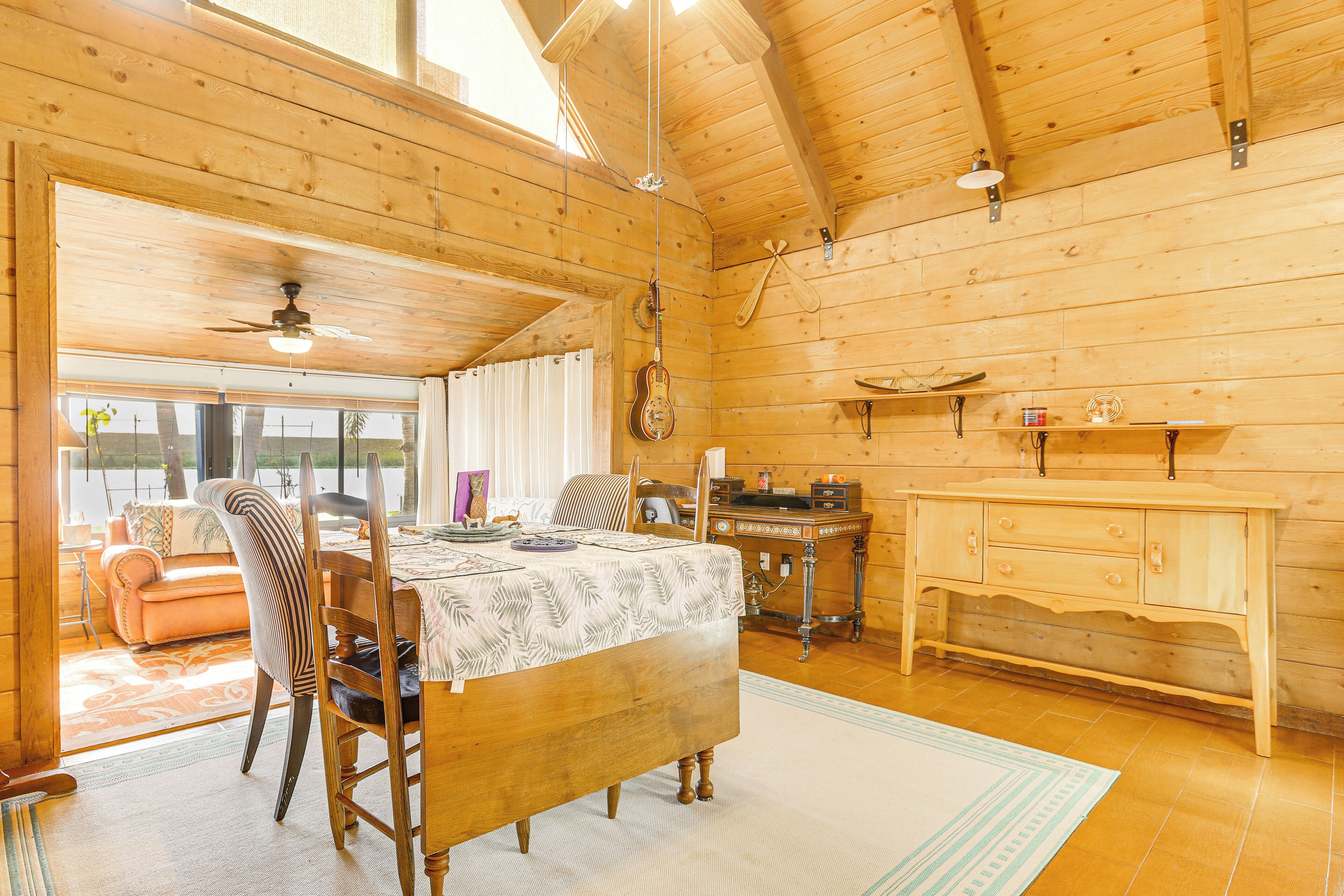 A wooden interior with a dining table, chairs, a ceiling fan, and a kitchen area with a wooden cabinet and countertop.
