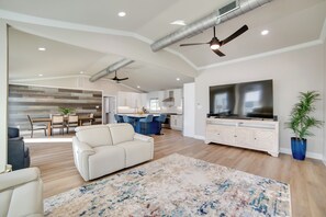 A spacious living area with a sofa, a large TV, and a dining area with a kitchen in the background. - Fish, Boat & Relax! Lake Fork Home w/ Shared Dock (Emory)