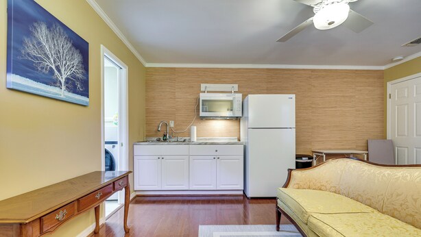 A compact kitchen with white cabinets, a microwave, and a refrigerator.