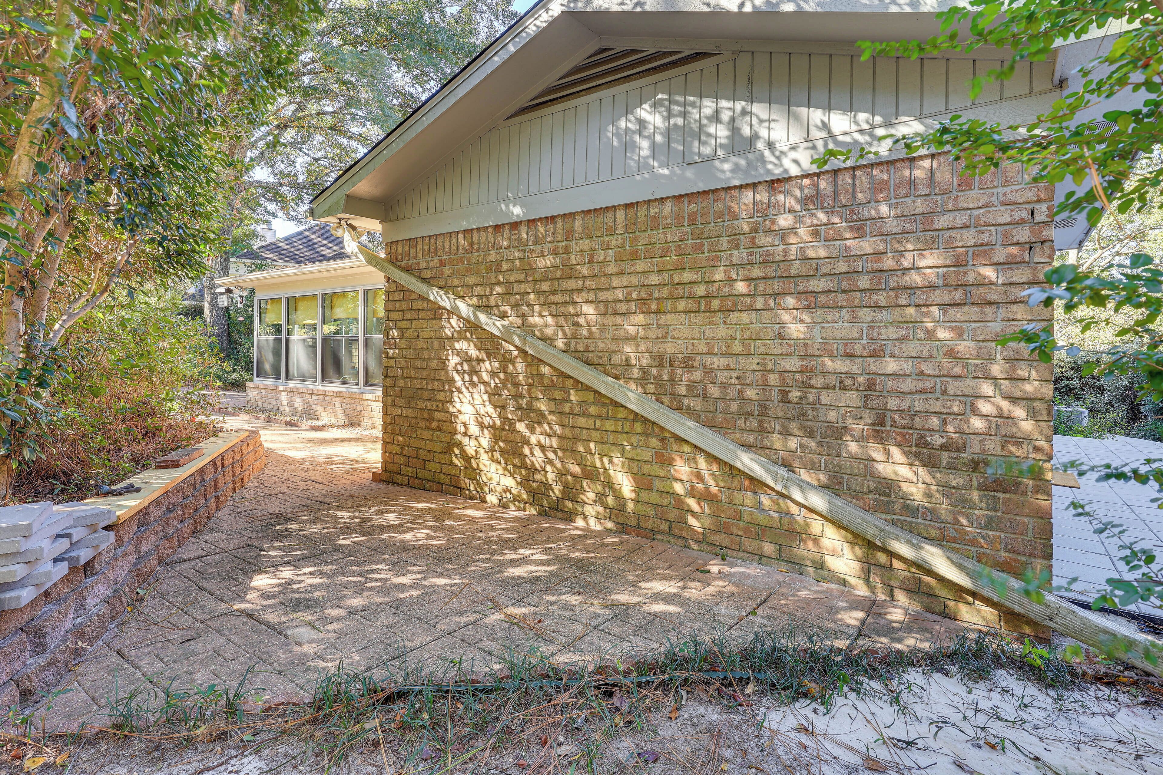 A brick exterior wall with a wooden deck and a window.