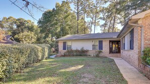 A single-story brick house with a front yard, a covered porch, and a garage.