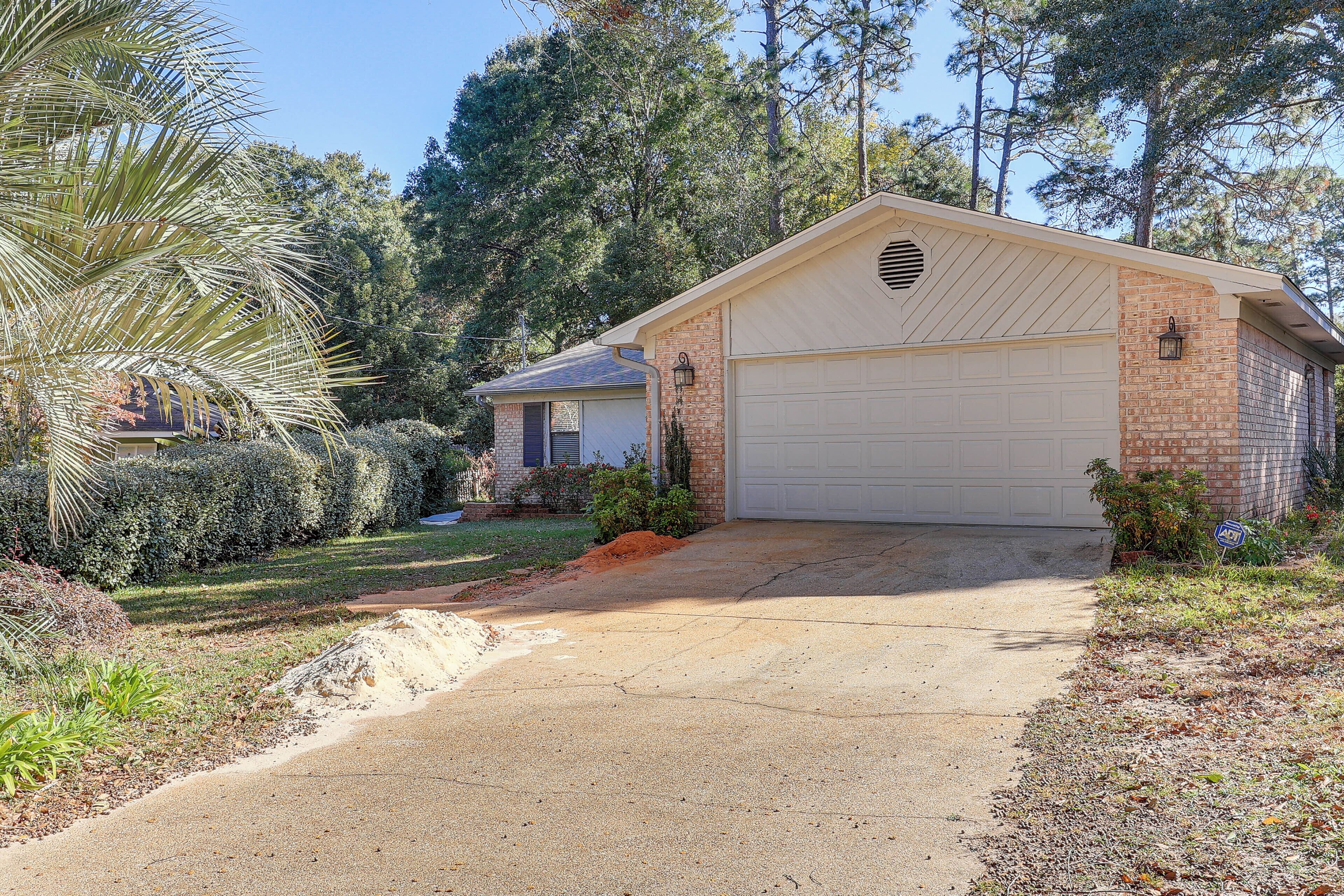 A single-story house with a garage, surrounded by a well-maintained lawn and trees.