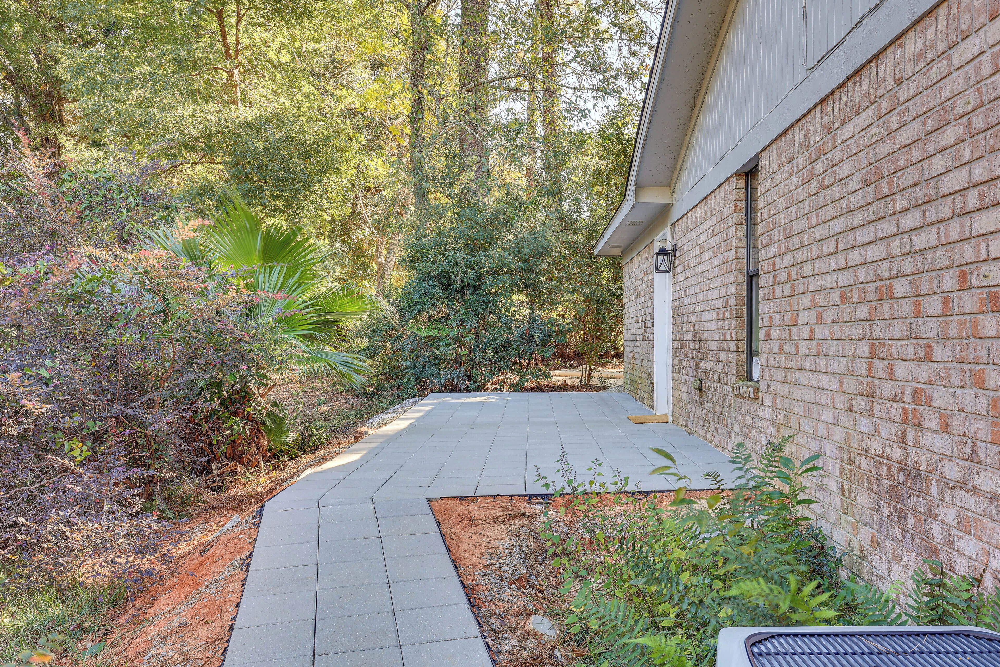 A paved pathway leading to a brick building with a window.