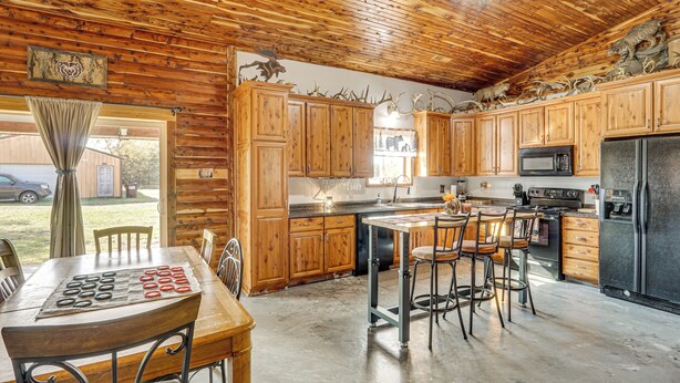 Une cuisine de style rustique, aménagée comme un chalet, avec des meubles en bois, une table à manger et des tabourets de bar.