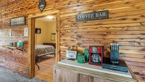 Un intérieur en bois avec une enseigne indiquant « Café » et un lit visible à travers une porte ouverte.