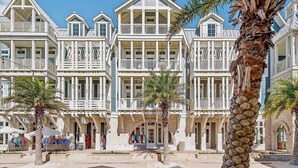 Ein Strandhotel mit mehreren Balkonen, Palmen und blauem Himmel.