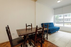 Ein Essbereich mit Holztisch und Stühlen, einem blauen Sofa und einem Fenster mit Blick.
