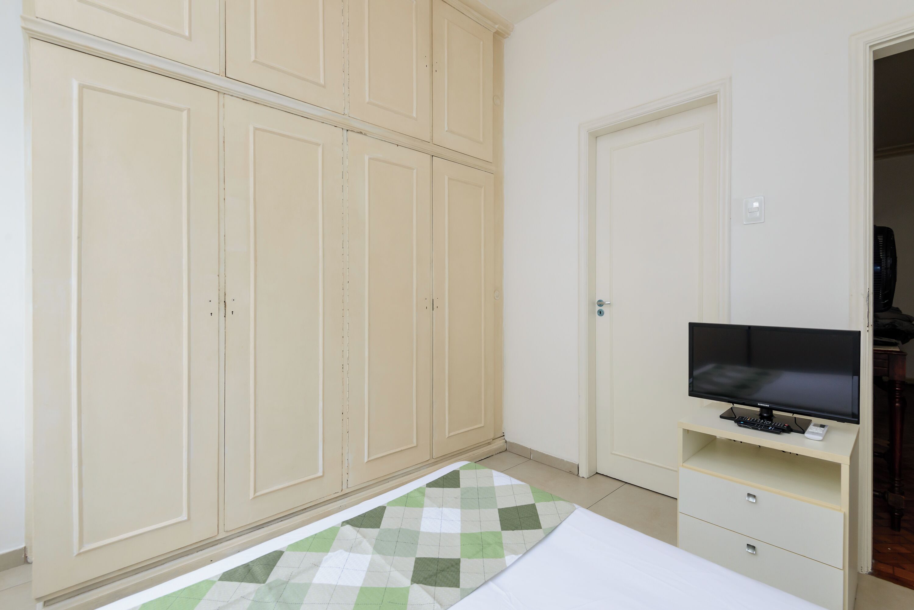 Ein Schlafzimmer mit einem Bett, einem Fernseher auf einem Schrank und einem Kleiderschrank.