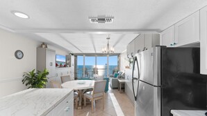 A modern kitchen with a large refrigerator, a dining area with a view, and a balcony with a view. - Rising Tides Properties Condo 1007 (Murrells Inlet)