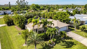 A residential area with multiple houses, well-maintained lawns, and palm trees.