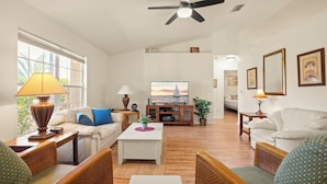 A living room with a ceiling fan, two sofas, a coffee table, and a television.