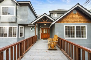 A wooden deck with two rocking chairs and a wooden door. - Big Bear Nest at Eagle Mountain - Game Room, Pool Table, Ping Pong, Foosball, Jet Tub, 3 Fireplaces (Big Bear Lake)