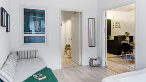 Ein modernes, minimalistisches Schlafzimmer mit Bett, Fenster und Blick in einen Essbereich.