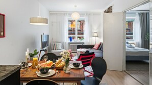 Ein modernes Wohnzimmer mit Essbereich, einer Couch und Blick auf die Stadt.