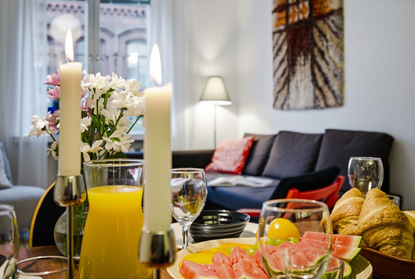 A breakfast setup with candles, flowers, and a variety of food and drinks on a table.
