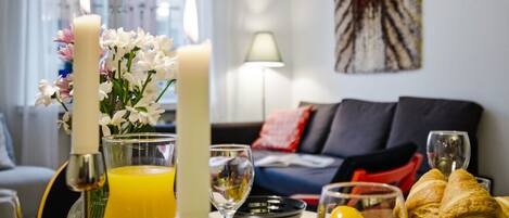 A breakfast setup with candles, flowers, and a variety of food and drinks on a table.