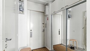 Hotelværelse med skydedør, en lille skammel, dørmåtte og et kontrolpanel på væggen.