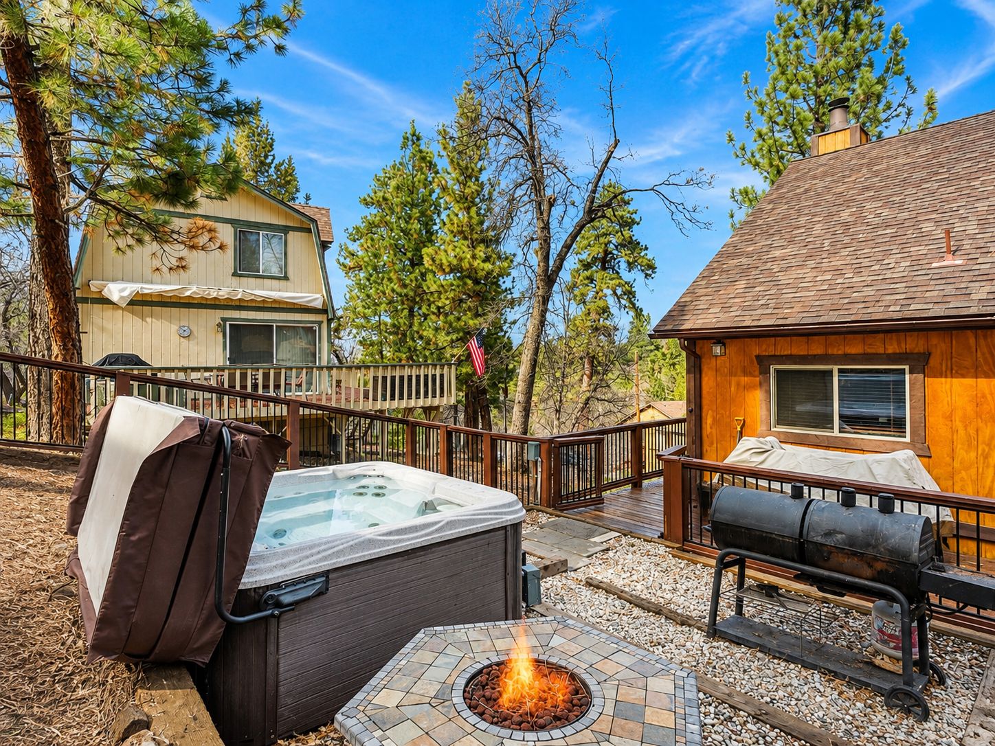 A hot tub, outdoor grill, and a deck with a wooden fence.