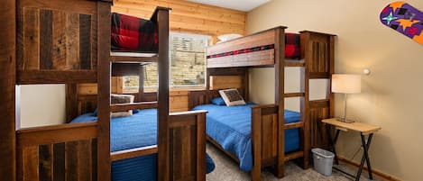 Habitación con literas, una ventana, una lámpara y un adorno en la pared.