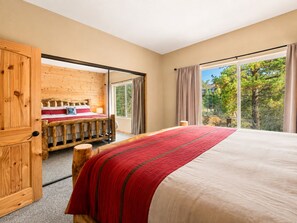 Een slaapkamer met een groot bed, een houten garderobe en een raam met uitzicht op bomen.