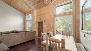 A wooden interior with a sofa, dining table, and chairs. - Bear State of Mind - Close to Ski Slopes, Hot Tub, Foosball, Fireplace, Deck, BBQ (Big Bear City)