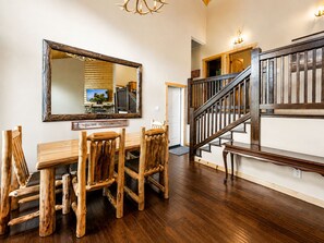 Ein Holzespeisesaal mit Stühlen, ein großer Spiegel und eine Treppe mit Holzwertungen.