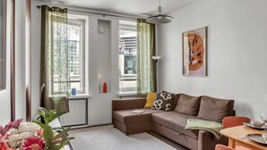Una sala moderna con un sofá marrón, una mesa de comedor con sillas y un ventanal con cortinas verdes.