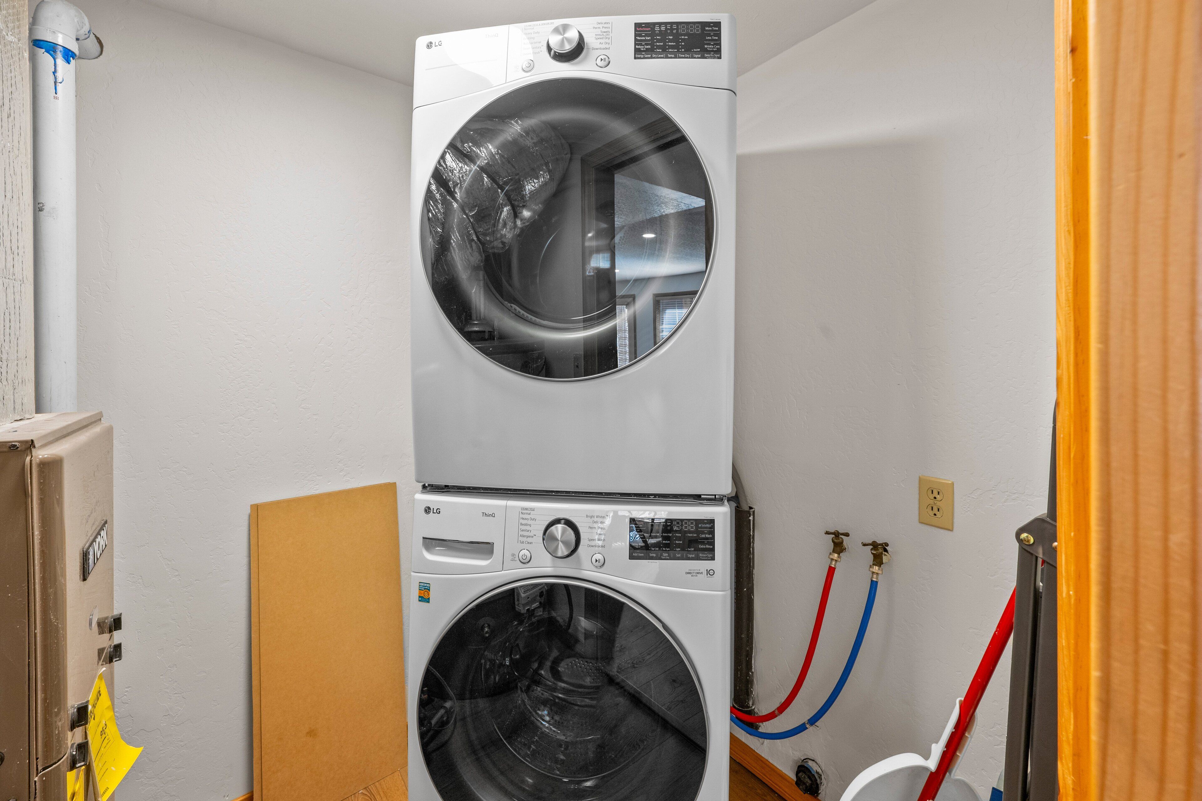 A stacked washer and dryer unit with visible control panels and hoses.