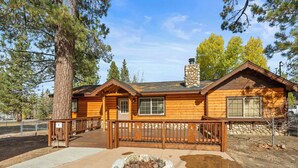 A log cabin with a stone chimney, wooden deck, and a fire pit. - Log Cabin Dream - Log Cabin, Walk to Lake, Fireplace, Deck, BBQ (Big Bear Lake)