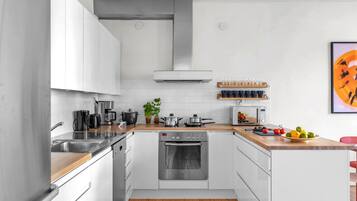 Eine moderne Küche mit weißen Schränken, Edelstahlgeräten, einer Holz Arbeitsplatte und einer Mikrowelle.