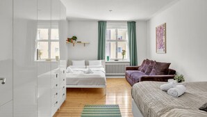 Een moderne slaapkamer met een bed, een bank, een radiator en een raam met gordijnen.